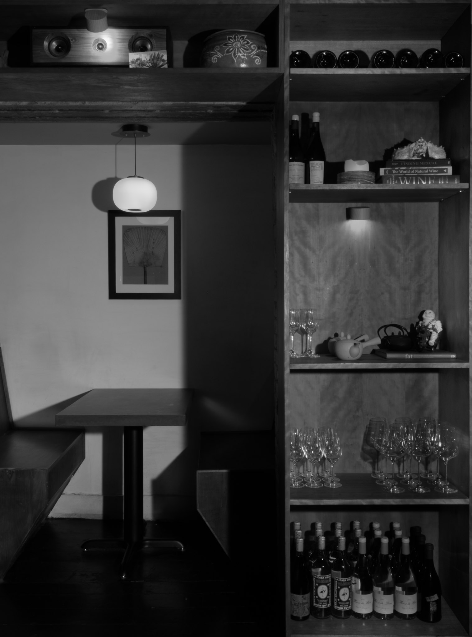 Corima dining nook — banquette and table beneath a pendant light beside a wine shelf